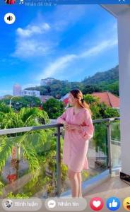 a woman in a pink dress standing on a balcony at Homeatay & Apartment CHÂU SƠN in Vung Tau