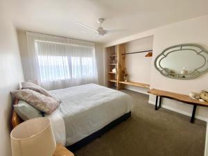 a bedroom with a large bed and a mirror at Ahipara Beach Pad in Ahipara
