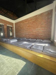 Cama grande en habitación con pared de ladrillo en Mộc Châu Mountain Retreat, en Làng Môn