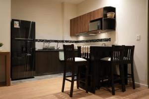 a kitchen with a bar with chairs and a refrigerator at Monoambiente de Lujo Cores in Cochabamba