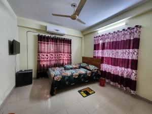 a bedroom with a bed and curtains and a tv at Aaira guest house in Dhaka