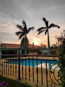 a fence with palm trees and a swimming pool at Finca Hacienda Casa Prada in Bucaramanga