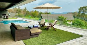 a patio with a table and an umbrella and a pool at Aroha Seaview Villa - Private Pool - in Pantai Cenang