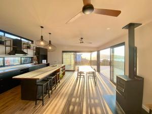a kitchen with a ceiling fan and an island with chairs at Ahipara Beach Pad in Ahipara