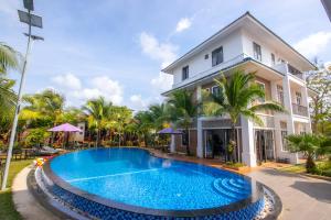 a villa with a swimming pool in front of a house at Hung Vuong Resort in Phú Quốc