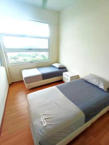 een slaapkamer met 2 bedden en een raam bij Sea view apartment level 21, sunrise view in Sandakan