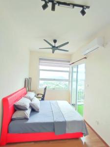 een slaapkamer met een rood bed en een plafondventilator bij Sea view apartment level 21, sunrise view in Sandakan
