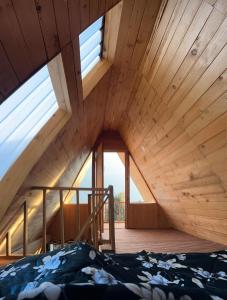 Cama en habitación con techos y ventanas de madera en Pinehill cottage en Jibhi