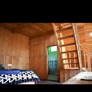 a room with a bed and a wooden wall at Pinehill cottage in Jibhi