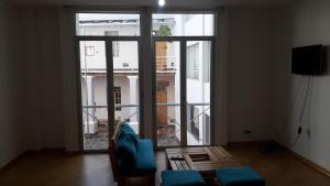 - un salon avec une grande fenêtre et des chaises bleues dans l'établissement Depto elegante y cómodo centro historico, à Quito