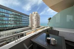 a table on a balcony with a view of a building at Marvelous Ocean View Suite Marina - By AppartAli in Casablanca