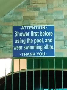 un letrero que dice ducha de atención primero antes de usar la piscina y llevar traje de baño en Villa Ceferina, en Tagbilaran City