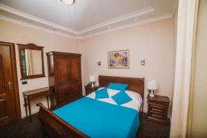 a bedroom with a blue bed in a room at Hotel Astoria in Tivat