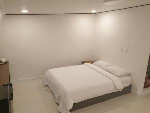 um quarto branco com uma cama com lençóis brancos em Seorak HOT Spring Mammoth Resotel em Sokcho