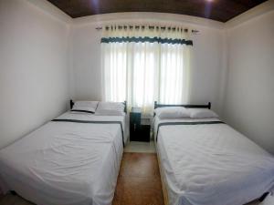 two beds in a small room with a window at Knuckles Range Bunglow in Kandy