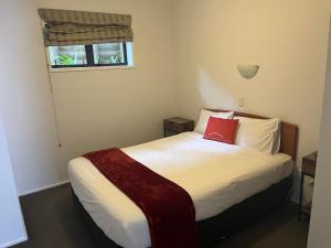 a bedroom with a bed with a red pillow on it at Ascot Motor Lodge in Wellington
