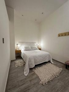 a white bedroom with a bed and a rug at Martita House in Clorinda