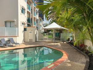 a swimming pool with an umbrella next to a building at CHA Private Apts Aruba Beach in Gold Coast