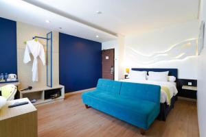 スラバヤにあるBonnet Hotel Surabayaのベッドルーム(ベッド1台、青いソファ付)