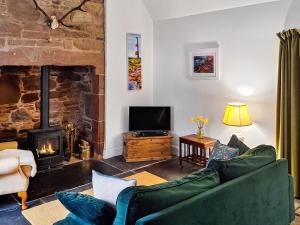 a living room with a couch and a fireplace at Old Manse Cottage in Auchterneed