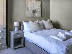 um quarto com uma cama com lençóis brancos e almofadas em Beck Cottage em Thirsk
