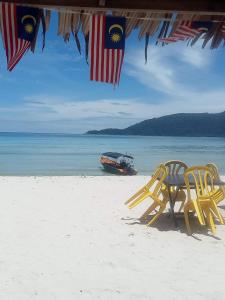 two yellow chairs and a boat on a beach at Matahari Chalet Long Beach Perhentian Island in Perhentian Islands