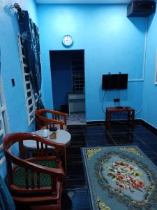 sala de estar con mesa, sillas y reloj en Maksu homestay en Kuala Nerang