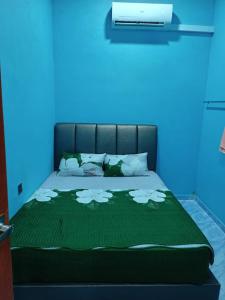 een bed met een groene deken met witte bloemen erop bij Maksu homestay in Kuala Nerang