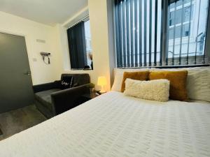 a bedroom with a large white bed and a couch at Centrally Located Stylish Studio Apt in Liverpool