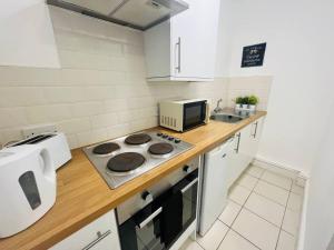 a kitchen with a counter with a stove and a microwave at Centrally Located Stylish Studio Apt in Liverpool