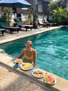 a woman sitting in a swimming pool with plates of food at White Coconut Resort in Gili Trawangan