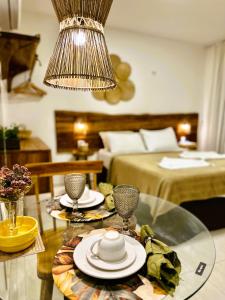 a room with a table with a chandelier and a bedroom at Suítes Jardins de Flecheiras in Flecheiras