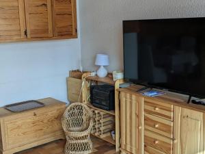 a living room with a large flat screen tv on a wooden entertainment center at Charmant T2 5 pers, Sud, balcon, TV, lave-linge, garage optionnel, calme à Orcières - FR-1-262-187 in Orcières