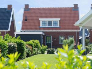 uma casa com um telhado vermelho e um quintal em Beautiful holiday home in Colijnsplaat with garden em Colijnsplaat