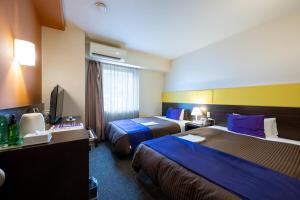 a hotel room with two beds and a television at Hotel 1-2-3 Takasaki in Takasaki