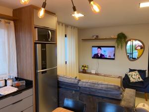 - un salon avec un canapé et une télévision dans l'établissement Apartamento com piscina a 100 metros da praia, à Governador Celso Ramos