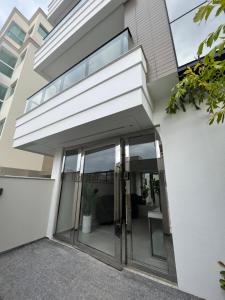 - une entrée pour une maison dotée de portes en verre dans l'établissement Apartamento com piscina a 100 metros da praia, à Governador Celso Ramos