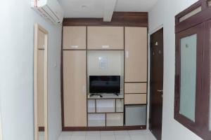 een kamer met een tv, kasten en een deur bij 555 Nangka Guest House in Jakarta