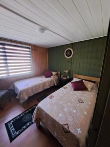 una camera con due letti in una stanza con soffitto di hospedaje a Puerto Varas