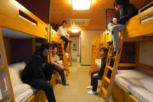 un gruppo di uomini seduti su letti a castello in una stanza di COGO Ryogoku a Tokyo