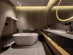 ein Badezimmer mit einer großen Badewanne und einem Waschbecken in der Unterkunft Jiangnan House Guanqianjie in Suzhou