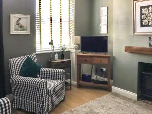 a living room with two chairs and a television at Beck Cottage in Thirsk