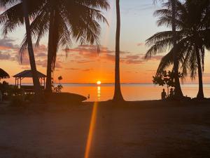 zachód słońca na plaży z palmami w obiekcie KoriKori House Fakarava w mieście Rotoava