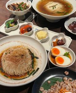 a table topped with plates of food with noodles and eggs at Jiangnan House Guanqianjie in Suzhou