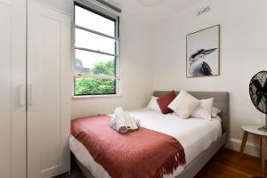 a bedroom with a bed with a red blanket and a window at Sunny Apartment in Surry Hills in Sydney