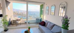 a living room with a couch and a large window at Vive Alto Reñaca in Viña del Mar