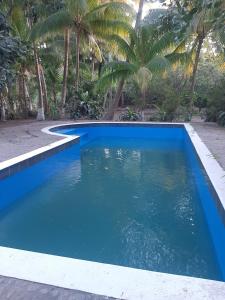a blue swimming pool with palm trees in the background at RANCHO SARIMAR in La Libertad