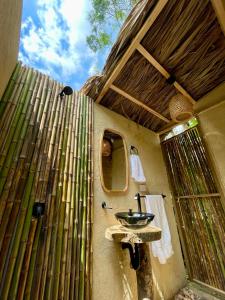 baño con lavabo y pared de bambú en ALMAH GLAMPING, en Cali