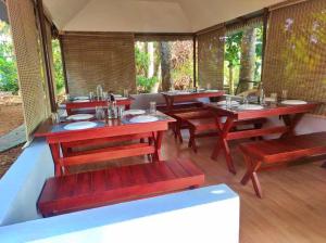 un restaurante con mesas de madera y bancos rojos en The Lake by Maat Hotels, en Alleppey