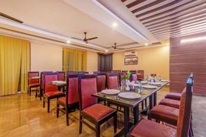 a restaurant with a long table and red chairs at Treebo Trend Expo Mart Inn - Greater Noida in Greater Noida